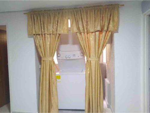a kitchen with yellow curtains and a washer and dryer at Piso 2-apartment near to Cali Airport in Palmira