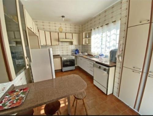 a kitchen with white appliances and a table in it at Passa Quatro- CASA INTEIRA RUSTICA para até 9 pessoas in Passa Quatro