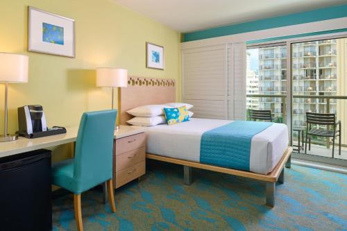 a bedroom with a bed and a desk and a chair at Aston Waikiki Circle Hotel in Honolulu