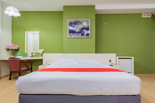 een slaapkamer met een groot bed met groene muren bij HOTEL 101 PERMAS JAYA in Johor Bahru