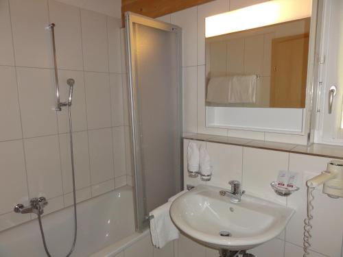 a white bathroom with a sink and a shower at Welcome Hotel Täsch by Täscherhof in Täsch