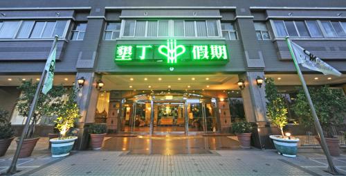 a hotel with a green sign on the front of it at Kenting Holiday Hotel in Hengchun
