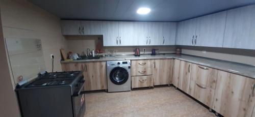 a kitchen with wooden cabinets and a washing machine at Hotel Garbani in Stepantsminda
