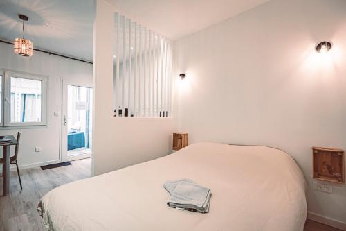 Dormitorio blanco con cama y mesa en SOCOTRA - Logement Climatisé en Centre-Ville, en Reims