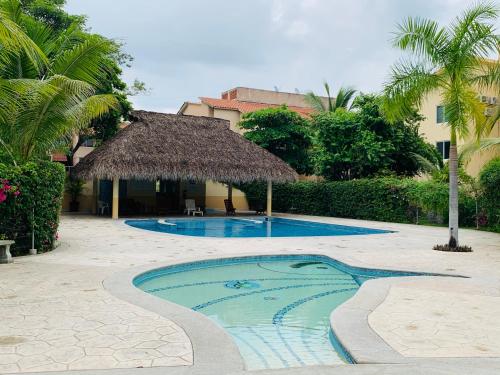 Una piscina con sombrilla de paja y un resort. en El Colorín, a condo in the heart of Huatulco, en Santa Cruz Huatulco