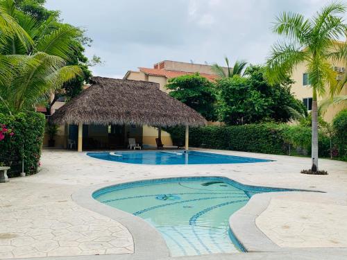 a swimming pool with a straw umbrella and a resort at El Colorín, a condo in the heart of Huatulco in Santa Cruz Huatulco