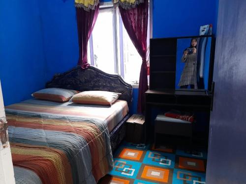 a blue bedroom with a bed and a window at PinkHomestay Ciwidey in Ciwidey