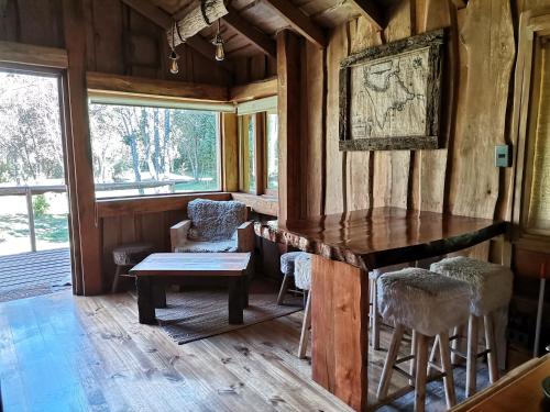 a room with a table and chairs in a house at Wonderful rustic cabin 2, with native logs, on the banks of the Trancura River in Pucón