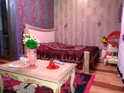 a bedroom with a bed and a table with flowers on it at Tubram S Ailəvi Qonaq Evi in Sheki
