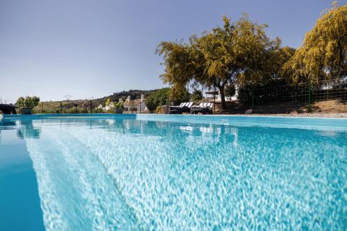 a large swimming pool with blue water at Rosas Cantares: Casa Maurus. in Pizarra