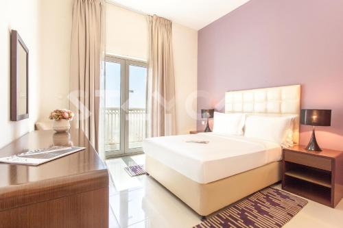 a bedroom with a bed and a desk and a window at Staycae Holiday Homes - Suburbia, Jebel Ali in Dubai