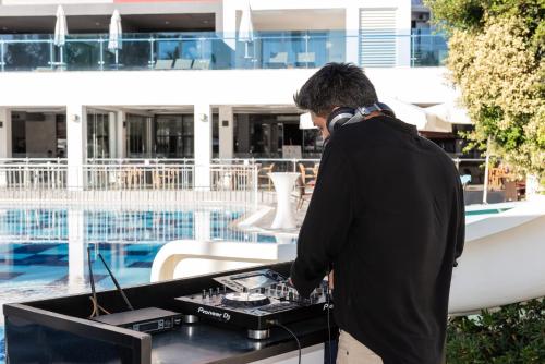 a man standing in front of a table with a computer at White City Beach Adult Only in Konaklı