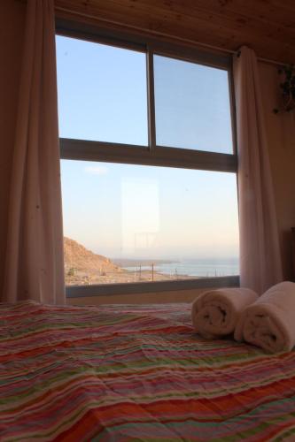 a bedroom with a bed with a large window at Dead Sea Rooftop - גג ים המלח in Ovnat