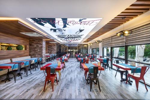 a restaurant with red and blue tables and chairs at White City Beach Adult Only in Konaklı