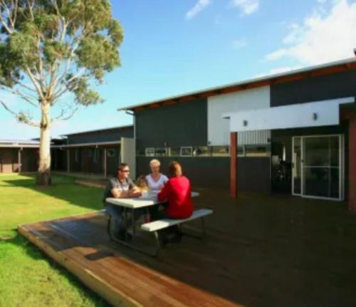 a group of three people sitting at a table on a patio at Swansea Backpackers in Swansea