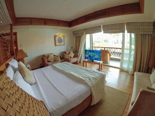 a bedroom with a large bed and a living room at Mövenpick Resort Aswan in Aswan