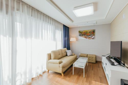 a living room with a couch and a television at Risen Ocean Park Hotel in Sokcho