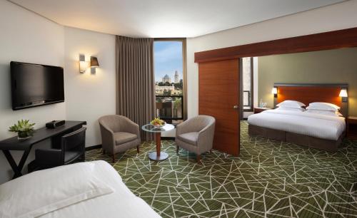 a hotel room with two beds and a television at The Inbal Jerusalem in Jerusalem