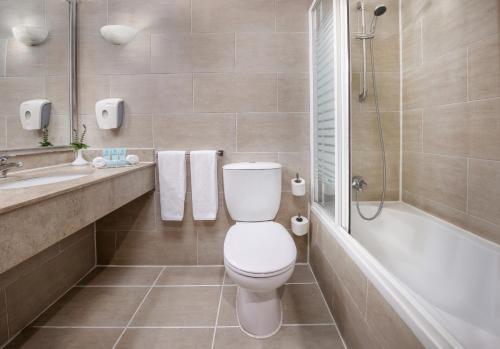 a bathroom with a toilet and a sink and a tub at Iberotel Luxor in Luxor