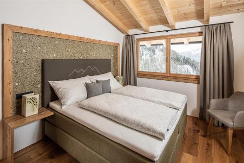 sypialnia z łóżkiem, oknem i krzesłem w obiekcie Bergsuite Pfaffenebner w mieście Matrei in Osttirol