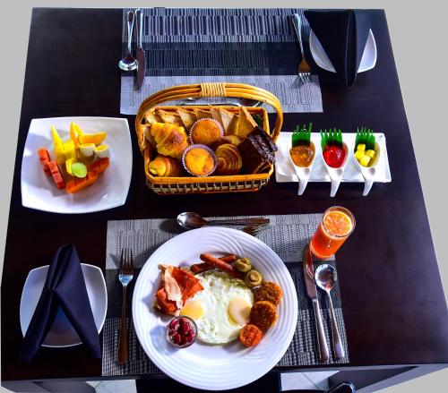 a table with plates of breakfast foods and a basket of food at Pine Hill Residence in Kandy