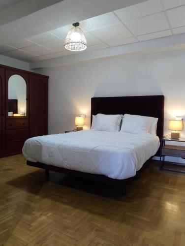 een slaapkamer met een groot wit bed met 2 lampen bij Casa del Beso II in Luarca