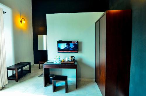 a room with a table and a tv on a wall at Pine Hill Residence in Kandy