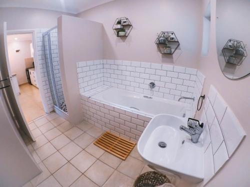 un bagno bianco con vasca e lavandino di Strelitzia Apartments a Westville