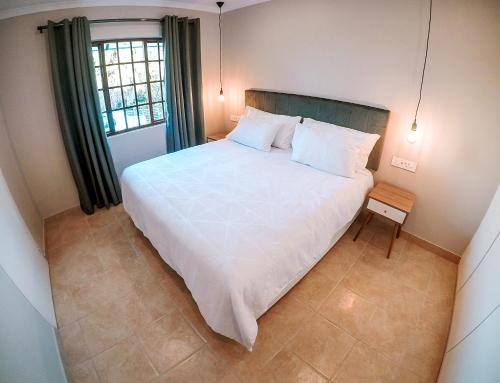 a bedroom with a large white bed and a window at Strelitzia Apartments in Westville