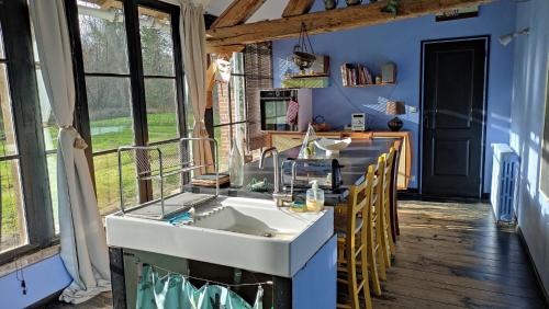 une cuisine avec un évier et un comptoir avec des chaises dans l'établissement Maison Bois Renard, à Saint-Laurent-Nouan