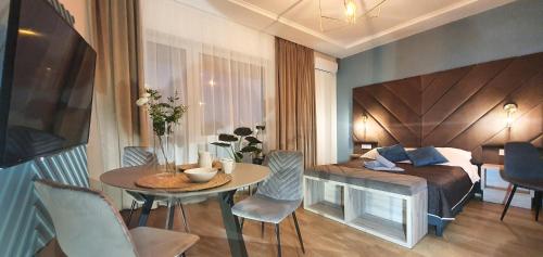 Habitación con cama, mesa y sillas. en DK Premium UkielPark, en Olsztyn