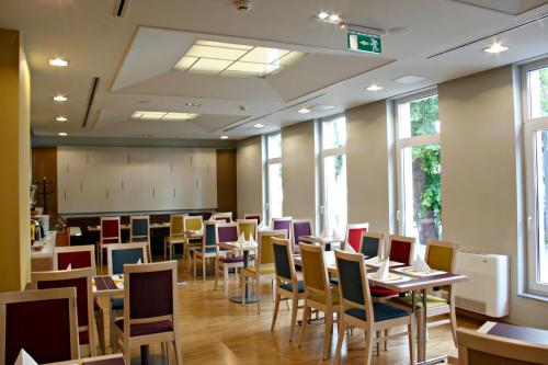 a dining room with tables and chairs and windows at Szent Gellért Hostel in Székesfehérvár