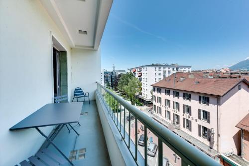 un balcon avec une table et une vue sur une ville dans l'établissement Allure - 2 bedroom apartment with balcony in the centre of Annecy, à Annecy