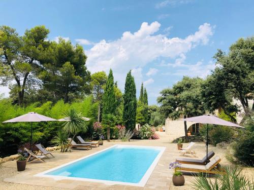 une piscine dans un jardin avec des chaises et des parasols dans l'établissement Maison Les Costes, à Vernègues