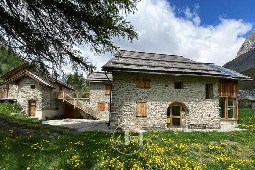une maison en pierre avec un escalier dans un champ dans l'établissement Le Fontenil - domaine de Serre Chevalier - 10 à 20 personnes, au Monêtier-les-Bains