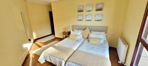 Schlafzimmer mit einem Bett mit weißer Bettwäsche und Kissen in der Unterkunft Cozy Yellow Home in Getxo in Getxo