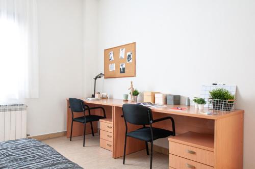 a desk with three chairs in a room with a bed at Residencia Universitaria Sant Jordi in Tarragona