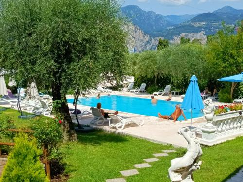 a group of people sitting around a swimming pool at Hotel Villa Isabella in Brenzone sul Garda