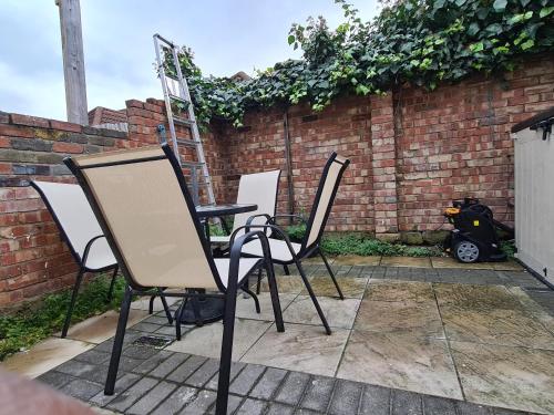 three chairs and a table in front of a brick wall at Umbrella Properties London Excel in London