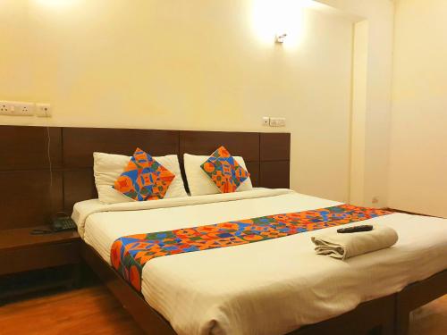 a bedroom with a large bed with colorful sheets and pillows at Hotel Merriment Alpha in Noida