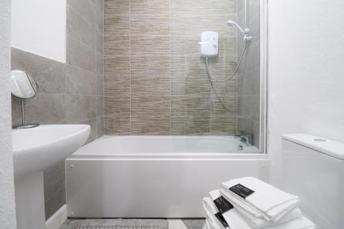 uma casa de banho com uma banheira branca e um lavatório. em Troon Golf Apartment em Troon