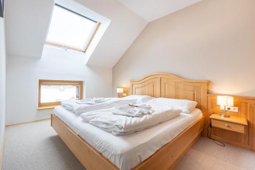 a bedroom with a bed with white sheets and a window at Apparthaus Sonnenberg in Haus im Ennstal