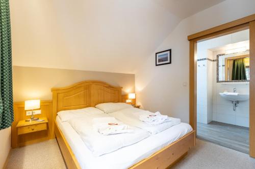 a bedroom with a white bed and a sink at Apparthaus Sonnenberg in Haus im Ennstal