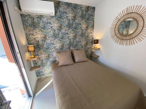 une petite chambre avec un lit et un miroir dans l'établissement La Siesta, à Mandelieu-la-Napoule