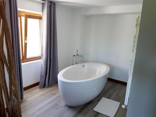 eine große weiße Badewanne im Bad mit Fenster in der Unterkunft Appartement d'une chambre avec terrasse a Sare in Sare
