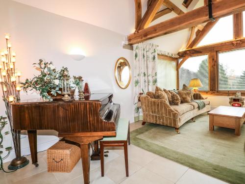 a living room with a piano and a couch at Swallows Barn in Chesterfield