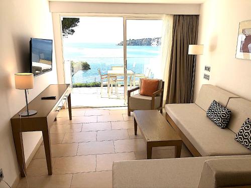 a living room with a couch and a view of the ocean at Aparthotel Ponent Mar in Palmanova