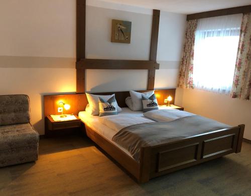 ein Schlafzimmer mit einem Bett, einem Stuhl und einem Fenster in der Unterkunft Landhaus Bichlbach in Bichlbach