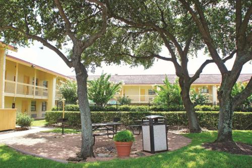 a park with a bench and trees in front of a building at Baymont by Wyndham Houston La Porte in La Porte