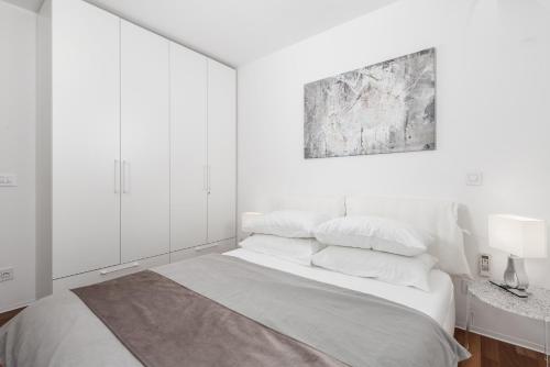 a white bedroom with a large bed with white walls at Apartment Mara Opatija with rooftop swimming pool in Ičići